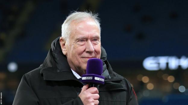Martin Tyler holding a microphone 